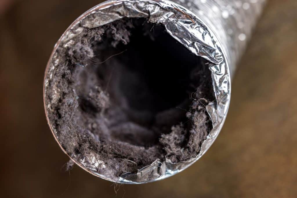 Close-up of a dust-filled HVAC air duct showing buildup that requires professional air duct cleaning.