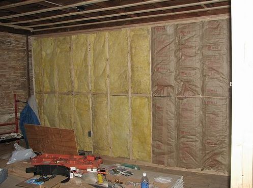 Wall framing filled with fiberglass batt insulation during home insulation installation.